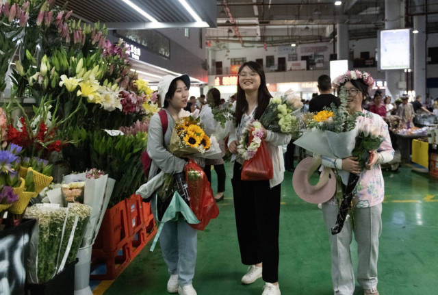 2023年7月13日，游客在昆明斗南花卉市场内购买鲜花。