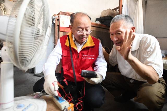 钱海军（左）义务为结对老人维修家里的老旧电器。新华社发（姚科斌摄）