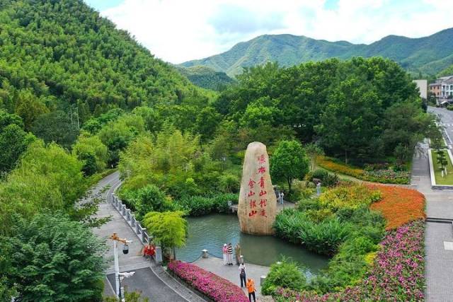 在浙江省湖州市安吉县余村，游客在刻有“绿水青山就是金山银山”的石碑前留影（2025年8月6日摄，无人机照片）。新华社记者 毛竹 摄