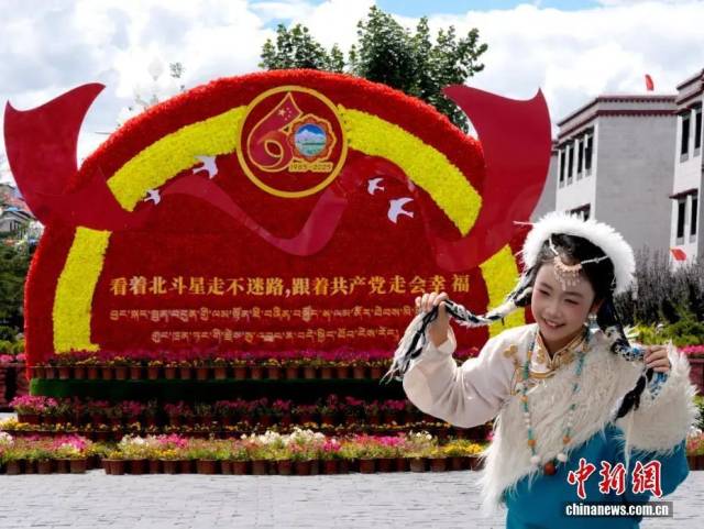 8月19日，随着西藏自治区成立60周年庆祝活动临近，拉萨氛围浓。图为游客在拉萨大昭寺广场上的大庆宣传标语前留念。中新社记者 李林 摄