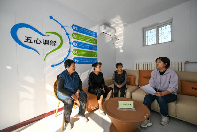 在天津市宁河区芦台街道金华路社区，社区党总支副书记吴蕊（右一）就社区监控设备安装问题为社区居民进行解答（2024年10月11日摄）。金华路社区积极践行新时代“枫桥经验”，将原社区居委会闲置用地提升改造成为联络群众的基层综合治理阵地——“解铃小院”。新华社记者 孙凡越 摄