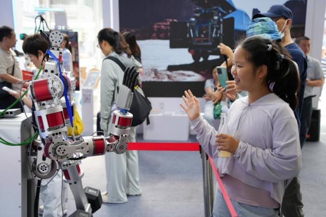 △2025年服贸会公众开放日第一天，参观服贸会的小朋友向机器人打招呼。