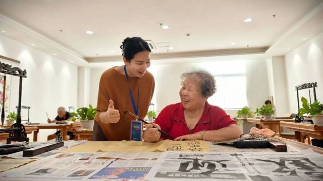 志愿者梁银霞陪老人练习书法。（受访者供图）