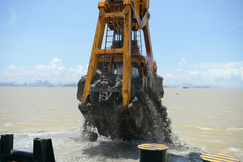 "金雄"轮巨大的抓斗从海底伸出水面,抓起满满一斗淤泥,泥水在海面上