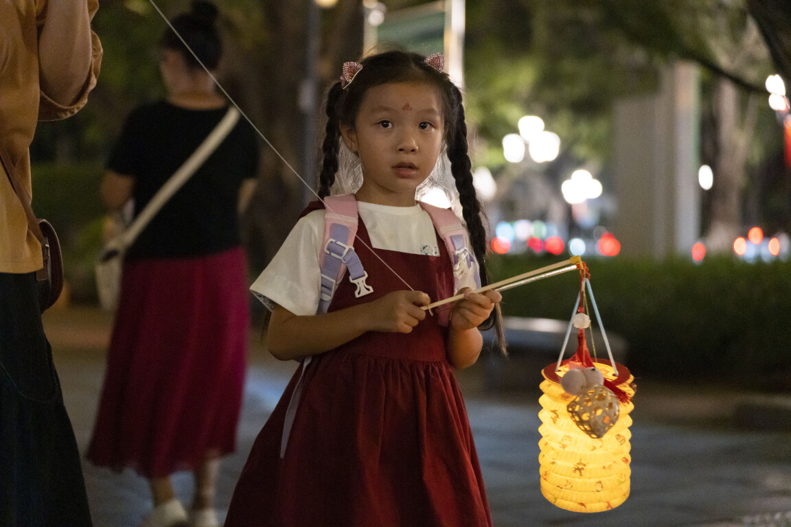 中秋夜，广州市民在滨江路珠江边赏月游玩，一位小朋友提着灯笼在行走。